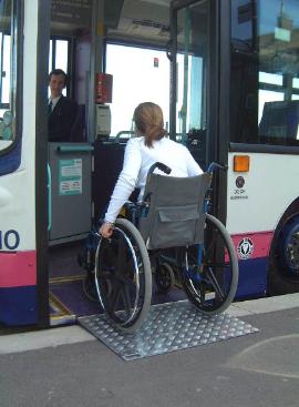 Woman using a manual wheelchair enters onto an accessible transit bus.
