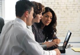 three people looking at a laptop
