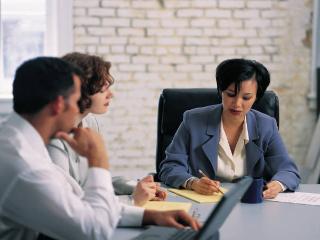 three people at a table discussing information